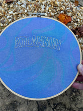 Load image into Gallery viewer, 8 Inch Silver &quot;Atlannuh&quot; Hand-Embroidered on Blue Oil Slick Iridescent Fabric Hoop
